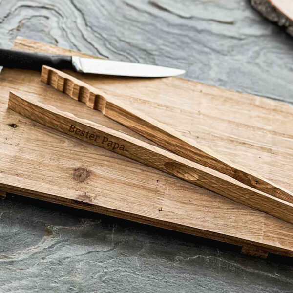 Stofftiger Grillzange Premium aus Eiche mit Gravur Bester Papa, auf Holzbrettern mit Messer