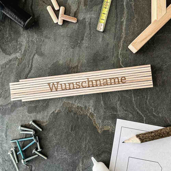 Stofftiger Zollstock Natur mit Wunschname, Nahaufnahme der Gravur auf Schiefer mit Dübeln und Schrauben