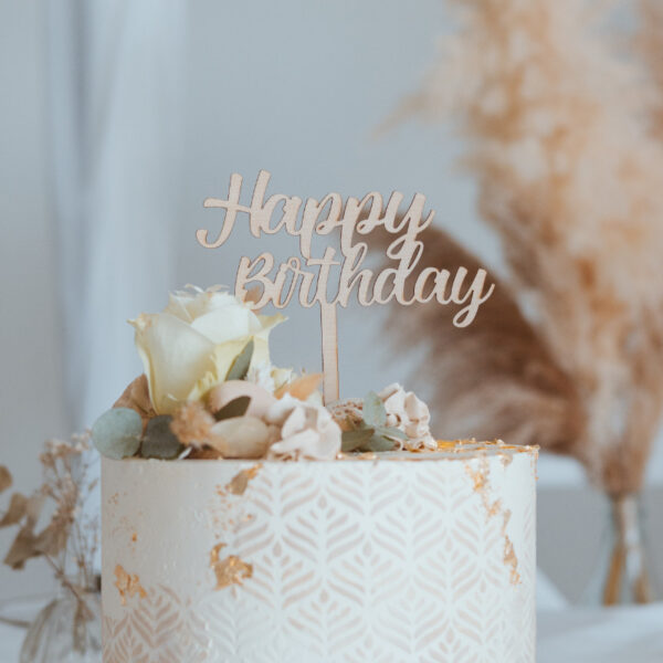 Stofftiger Caketopper Happy Birthday in Schreibschrift auf einer weißen Torte mit Rosen und Pampasgras
