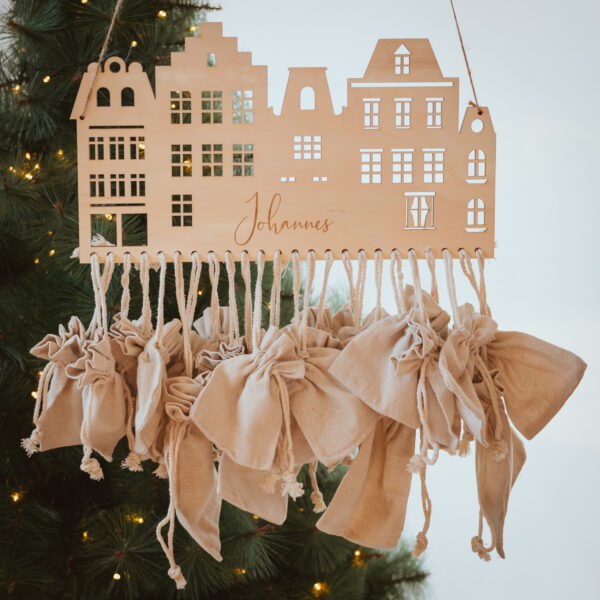 Stofftiger Adventskalender Häuser aus Holz mit Name Johannes, Häuserzeile mit 24 Stoffsäckchen vor dem Christbaum
