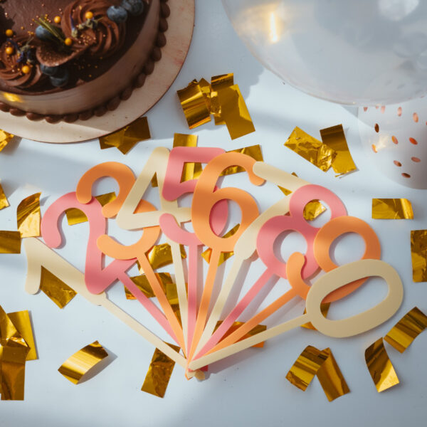 Stofftiger Caketopper Zahlenset mehrfärbig Rosa, alle Zahlen in Rosa- und Orangetönen aufgefächert auf Konfetti