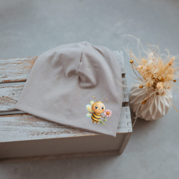 Stofftiger Haube grau Biene, graue Jerseyhaube mit kleinem Bienenmotiv auf Holz