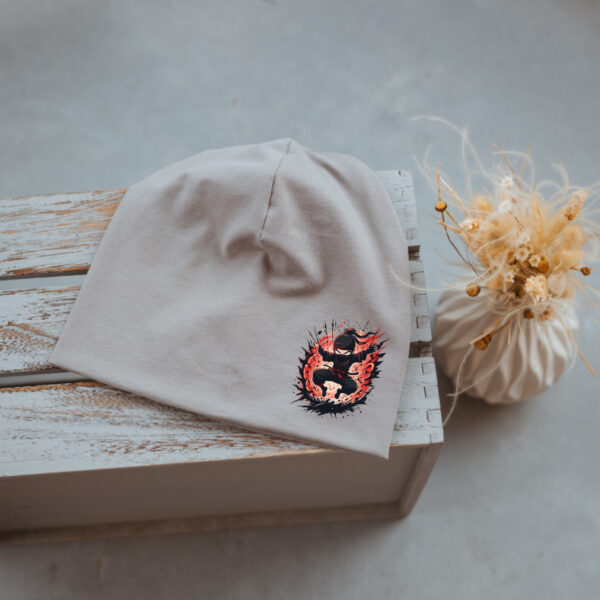 Stofftiger Haube grau Ninja, graue Jerseyhaube mit kleinem Ninjamotiv auf Holz