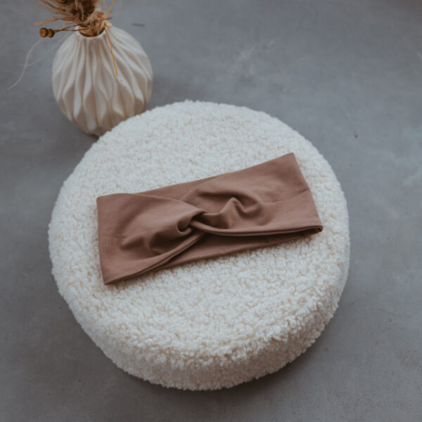 Stofftiger Knoten-Stirnband Taupe, taupefarbenes Stirnband mit Knoten auf einem Kissen