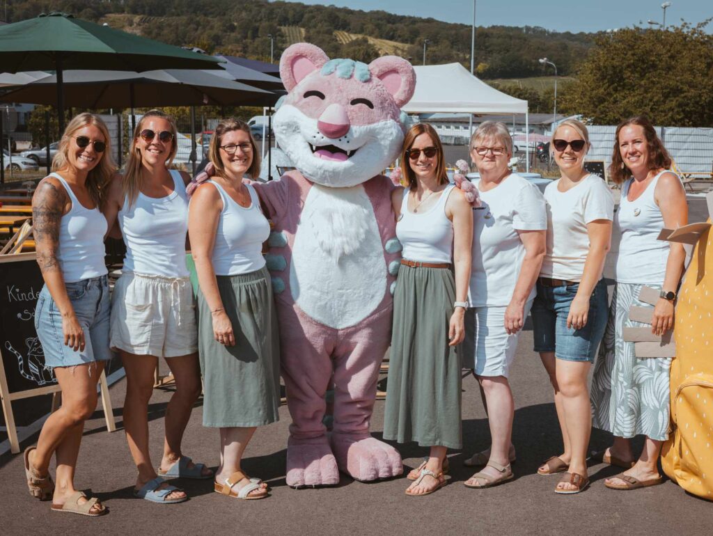 Das Stofftiger Team beim Sommerfest im Freien, daneben ein großes Kuscheltier